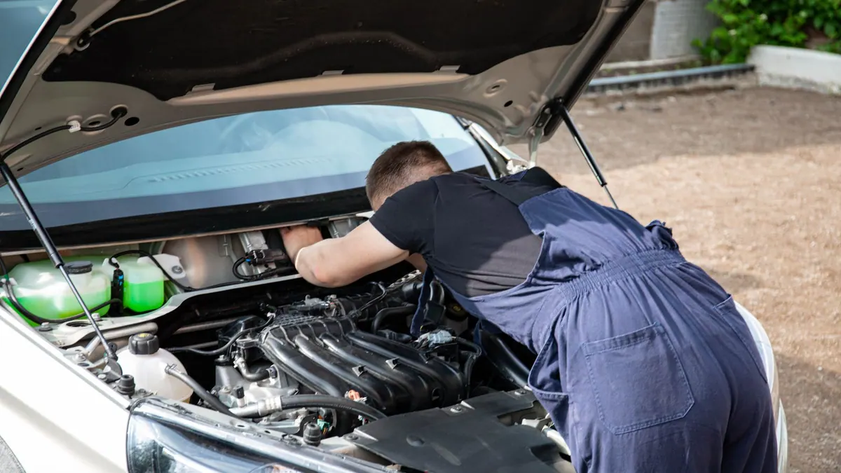 Mécanicien en bleu de travail réparant un moteur en extérieur