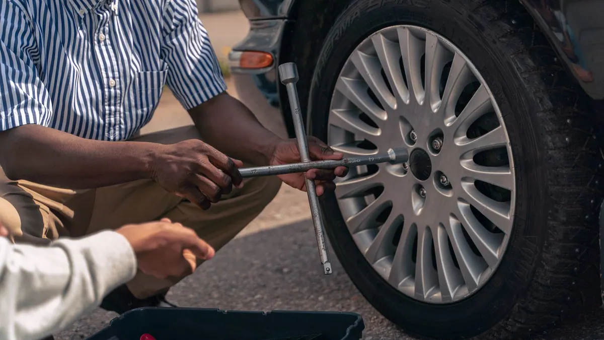 Changement d’une roue : un adulte montre le geste à un adolescent